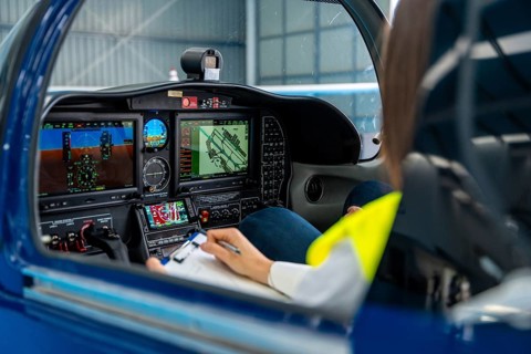 Pilot inspecting and documenting preflight checklist in a light aircraft cockpit, focused on