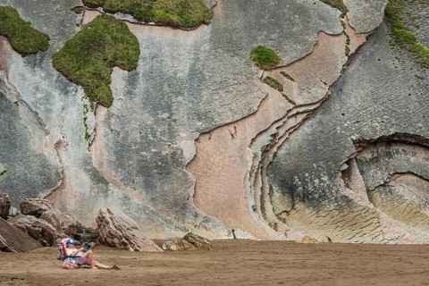 Relaxed holidaymaker in front of rocky cliffs as a geological formation made of rock layers, Flysch