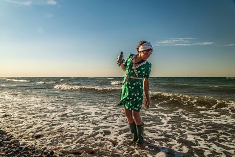 A woman (54) wearing a green tennis dress and green wellies is standing in the Baltic Sea, Germany
