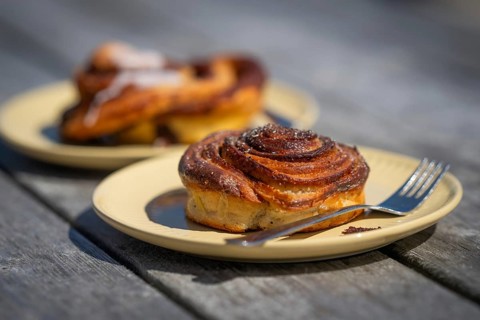 Cinnamon roll and fork lie on a light yellow plate, Houvig, Ringkøbing Fjord, Denmark