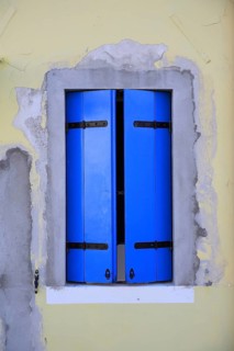 Modern window with blue shutters on yellow wall, renovated impression through distinctive colors,