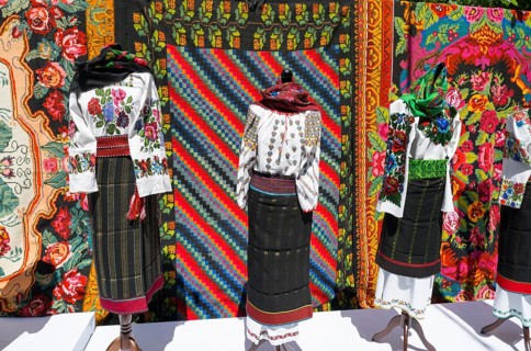 Traditional clothing and colorful tapestries in the background, folklore festival, Chisinau,