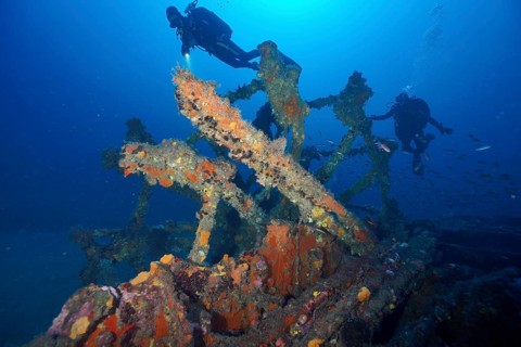Divers float over an overgrown wreck in the deep blue sea, dive site Wreck Ville de Grasse, Hyères,