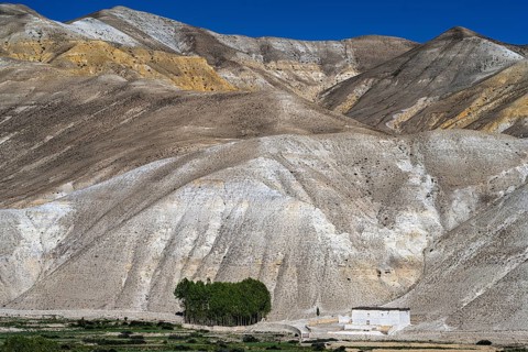 Traditional house in front of mountain landscape, erosion landscape near Lo Manthang, Mustang,