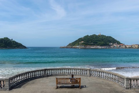 Woman sitting on a bench on the promenade at Bicentennial Balcony, La Concha beach, San Sebastián,
