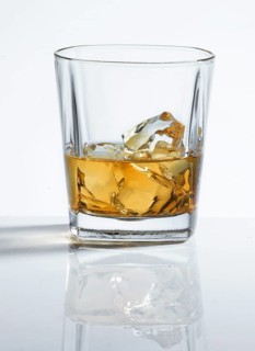 Whisky on the Rocks in a tumbler against a white background, studio shot