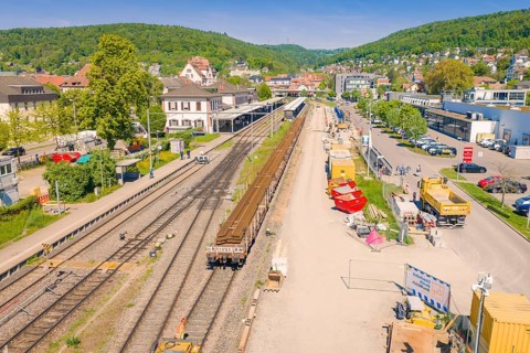 Aerial view of a train station with parallel tracks and surrounding buildings, electrification of