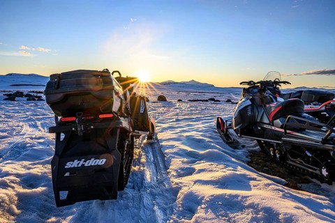 Ljungdalen, Jämtlands län, Sweden, Three snowmobiles stand in the setting sun that brings warm