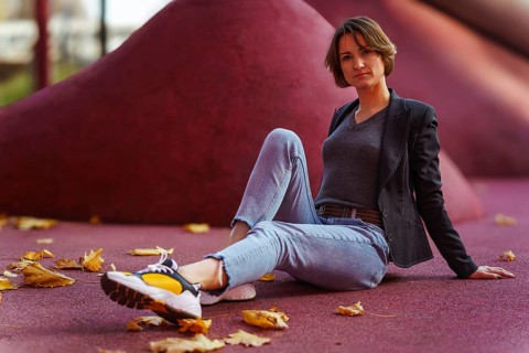 Relaxed young woman sitting among autumn leaves on red background