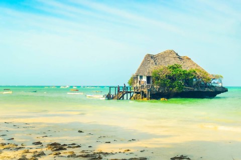 Unique wooden restaurant structure built on coral rock outcrop in turquoise Indian Ocean waters