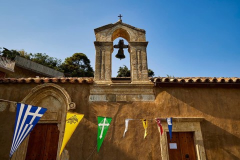 Small bell tower with colorful flags against a clear sky, Meronas village, Meronas, Amari Basin,