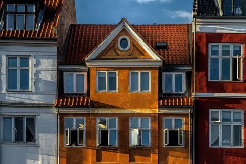 Nahaufnahme von bunten historischen Fassaden mit geöffneten Fenstern im Sonnenlicht, Kopenhagen,