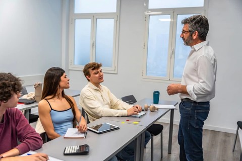 Experienced teacher standing and presenting to attentive young adult students sitting at individual