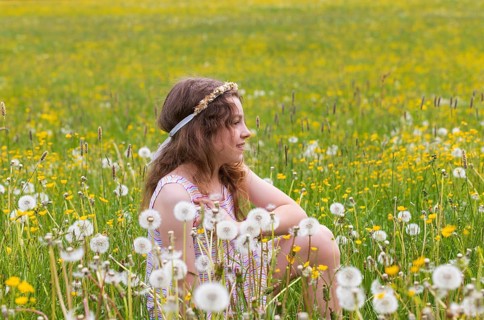 Portrait of a smiling girl sitting in a flower meadow, Mondsee, Salzkammergut, Austria