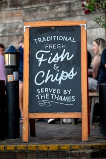 Fish & chip sign in front of an outdoor restaurant on the Thames, South Bank, London, England,