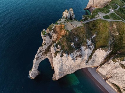 Aerial view, top down view of the Porte d'Aval rock formation in the evening sun, a landmark on the