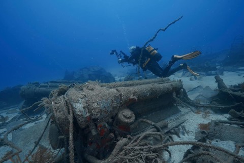 A diver examines a sunken wreck on the ocean floor, meteor wreck dive site, Russian hydrofoil,
