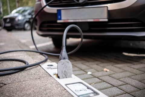 An e-car is charged with a cable at a charging curb on the KÖ, Düsseldorf, Germany
