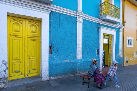 Woman and child, indigenous population, Aymara, sitting on a bench in front of a blue-painted house