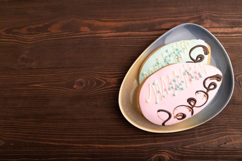 Glazed pink and blue decorated cookies, on brown wooden background, copy space, top view, flat lay