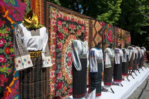 Traditional clothing in front of tapestries with folk patterns, folklore festival, Chisinau,