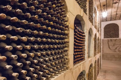Tight rows of wine bottles in an underground wine cellar, neatly stored in compartments, wine