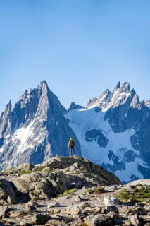 Young man in front of impressive mountain landscape in morning light, reflection in the Lac Blanc