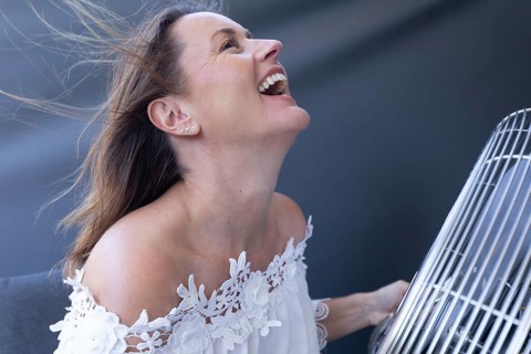 Woman enjoying cool airflow from a fan in a bright indoor portrait. during hot weather at home