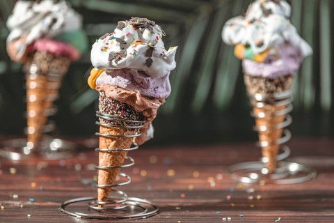 Colorful ice cream in waffles in metal holders decorated with cream and sprinkles