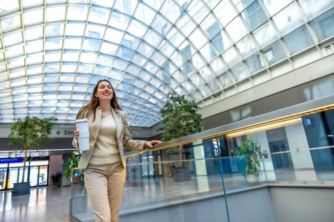 Young professional businesswoman walking confidently through a modern glass roofed transit hub,