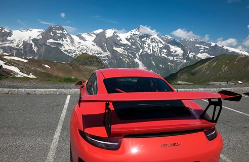 Red Porsche GT3 RS sports car in the Grossglockner High Alpine Road parking lot in front of