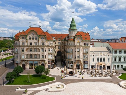 Large Baroque style building complex with red roofs and green dome on an urban square, aerial view,