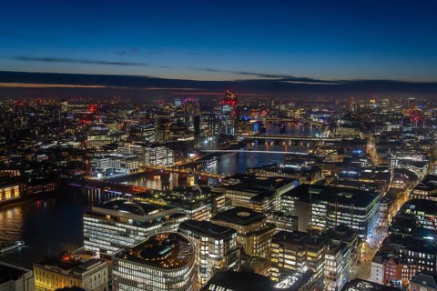 Aerial view over the River Thames and skyline showing illuminated skyscrapers and highrise