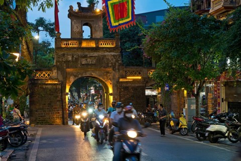 City gate during the evening rush hour on a busy street with mopeds, scooters, motorbikes and