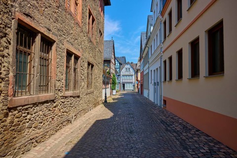 Narrow old town alleyway with half-timbered houses and cobblestones under blue sky, Eltville am