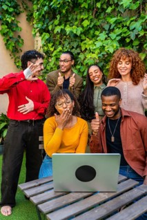 Diverse friends gathered on an outdoor patio, smiling and engaging in a supportive virtual group