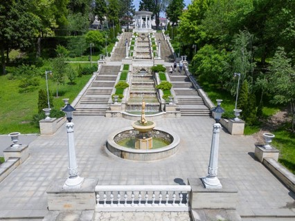 A classic park with a symmetrical staircase and central fountain surrounded by greenery aerial