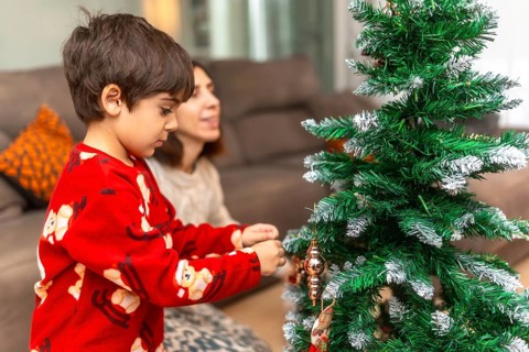 Mother and son creating holiday memories and bonding while decorating a festive christmas tree