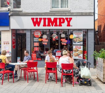 People sitting on street outside Wimpy fast-food restaurant, town centre of Felixstowe, Suffolk,