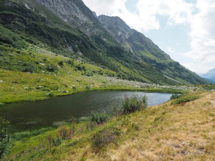 Small mountain lake, Halsesee, surrounded by green meadows and steep cliffs, Binntal Landscape