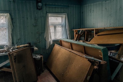 The room of an abandoned old village house with a pile of old broken furniture and other rubbish.