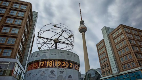 View of the World Clock and the Berlin TV Tower with surrounding buildings on a cloudy day,