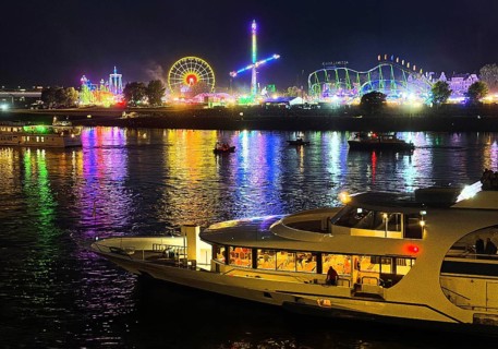 Rheinkirmes, largest funfair on the Rhine with rides, view across the river with boat at night,