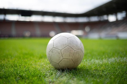 White soccer ball lying on the grass at stadium in Lubin, Poland