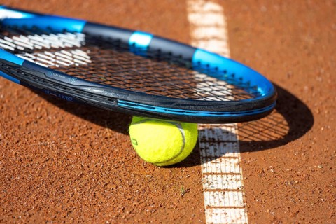 Tennis icon: close-up of a tennis ball and tennis racket on a clay court
