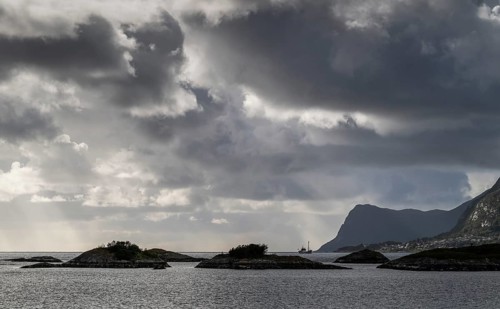 Dramatic lighting, dark clouds, islands and archipelago off the coast near Ålesund or Alesund, Møre