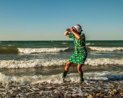A woman (54) wearing a green tennis dress and green wellington boots is standing in the Baltic Sea