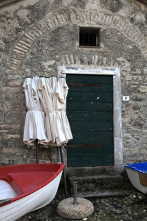 Rest in pre-season, folded umbrellas and a fishing boat ashore in front of a building. Tellaro,
