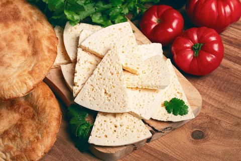 Georgian sliced cheese, on a wooden chopping board, with tomatoes with herbs and lavash, rustic