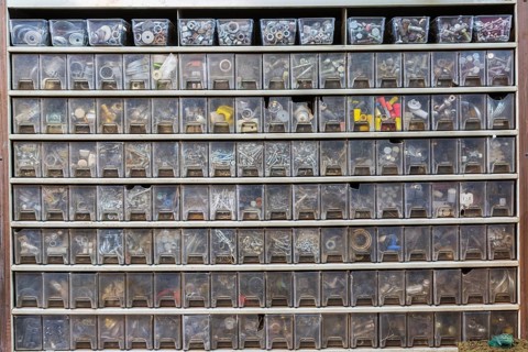 Cabinet with rows of plastic parts drawers showing washers, nuts screws, wire connecting caps in